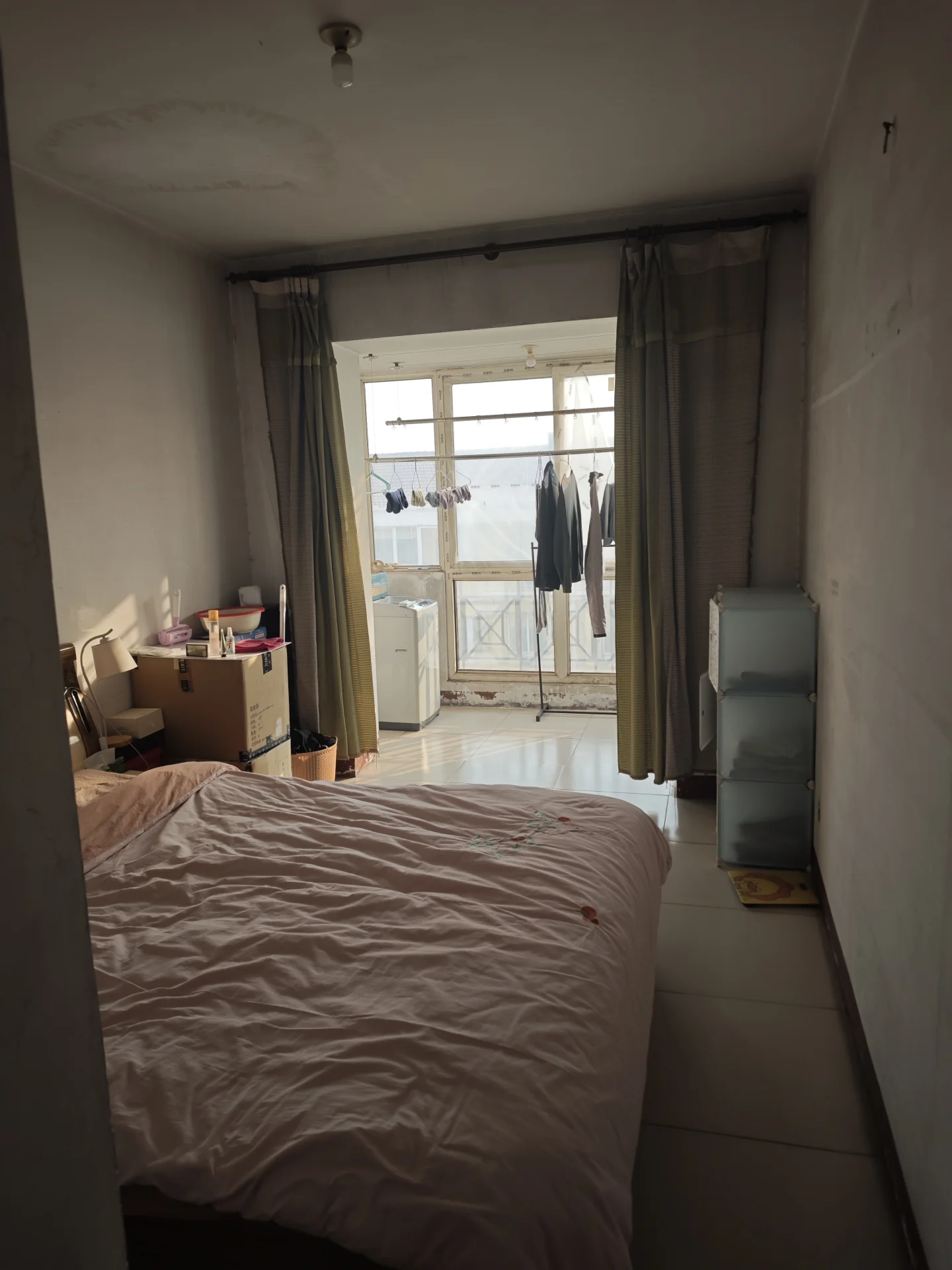 卧室空间，房间内摆放有大床和衣柜，地面为浅色瓷砖。采光适中，整体装修风格偏基础实用型。