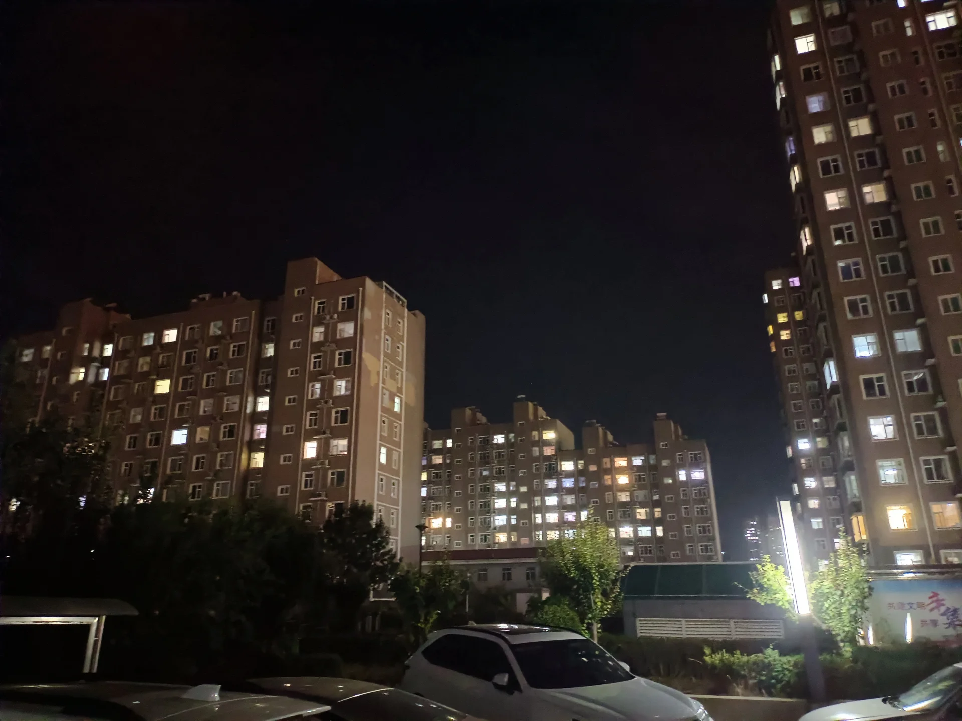 多栋高层住宅在夜间灯火通明，建筑风格偏向现代简约的居住环境，整体氛围宁静而繁华。