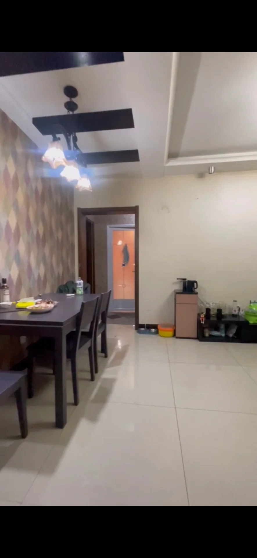 这是一个开放式餐厅和厨房区域，用餐区配有深色餐桌和椅子，墙面采用几何图案装饰。空间采光良好，整体装修风格偏向现代简约，环境整洁。