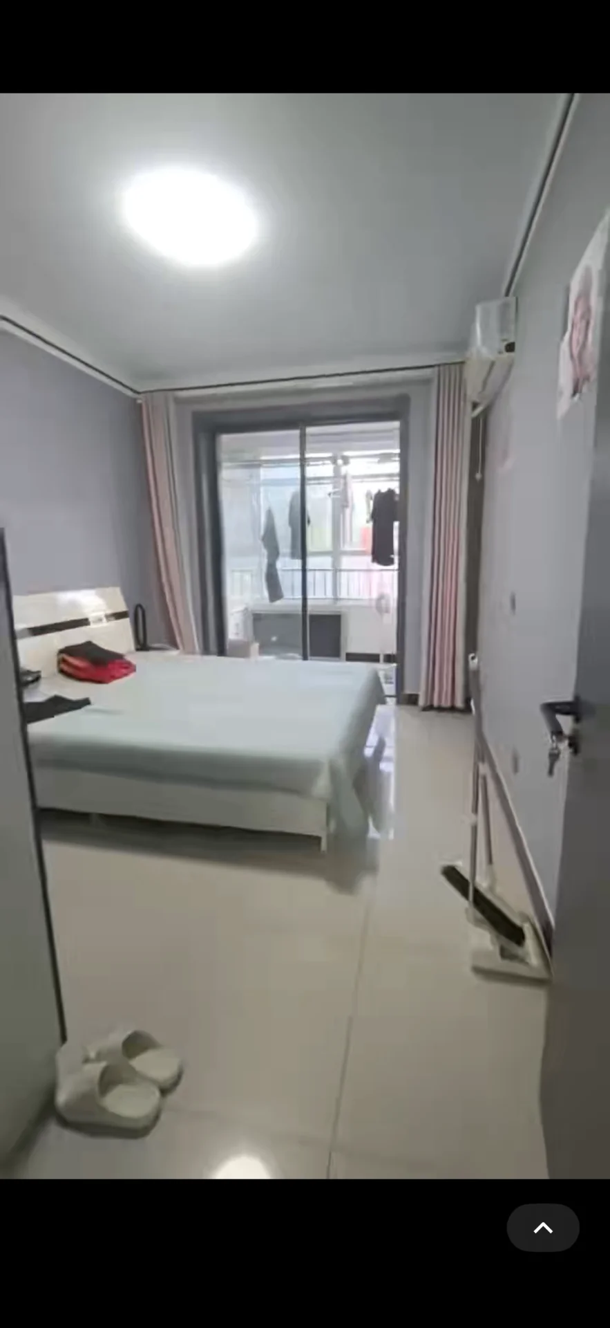 卧室空间，床铺为白色大床，墙面和地面采用浅色调设计。房间采光良好，整体呈现简洁明亮的现代风格。