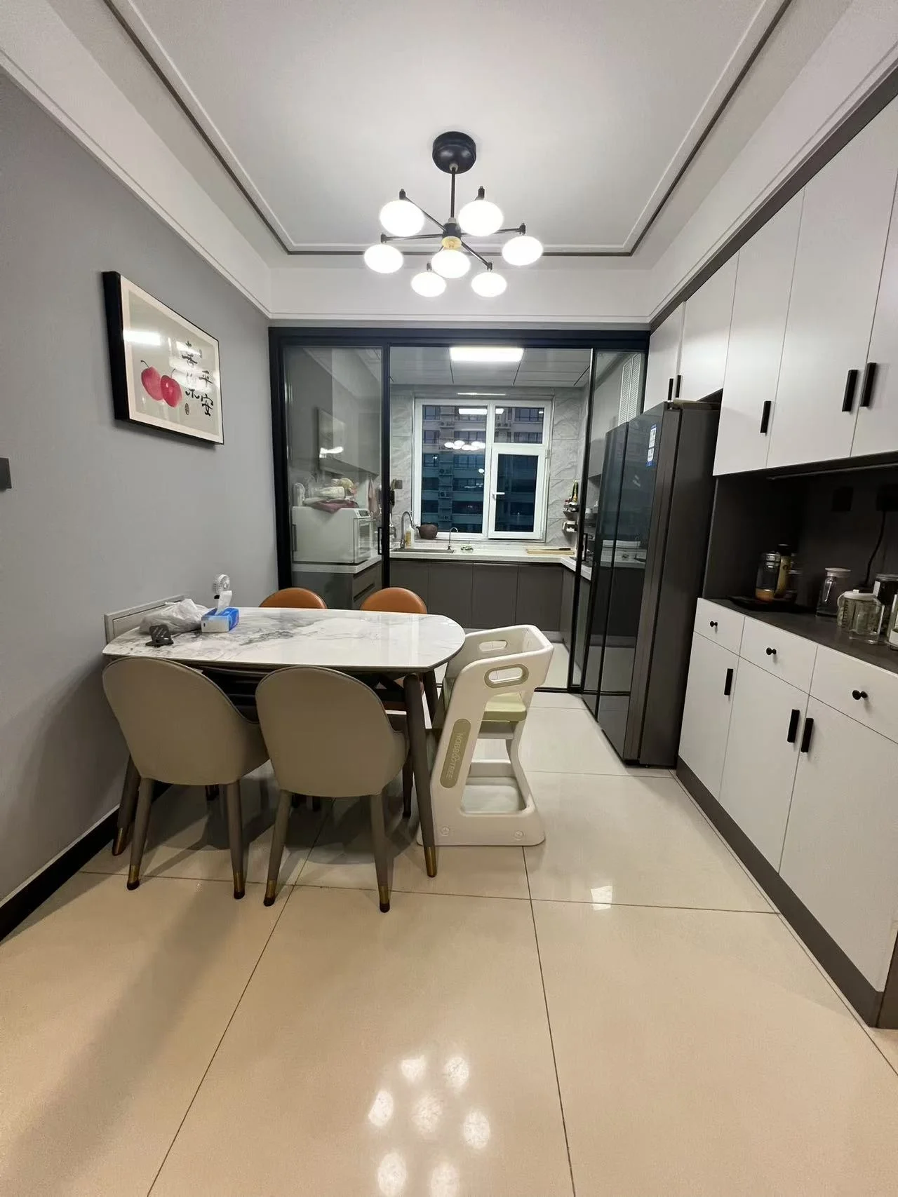 厨房和餐厅一体化空间，采用浅色调瓷砖铺设地面，配备白色橱柜和不锈钢电器。餐桌区域配有简约风格的餐椅，整体采光良好，装修风格偏向现代简洁。
