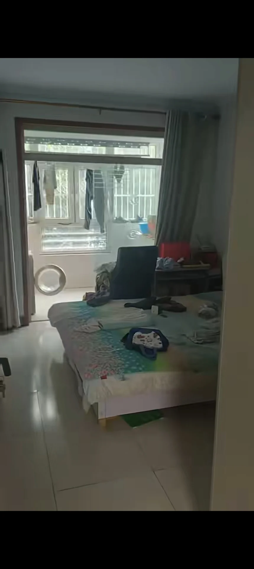 卧室空间，地面为浅色瓷砖，配有单张床和衣柜等基础家具。采光良好，整体呈现简洁的基础装修风格。