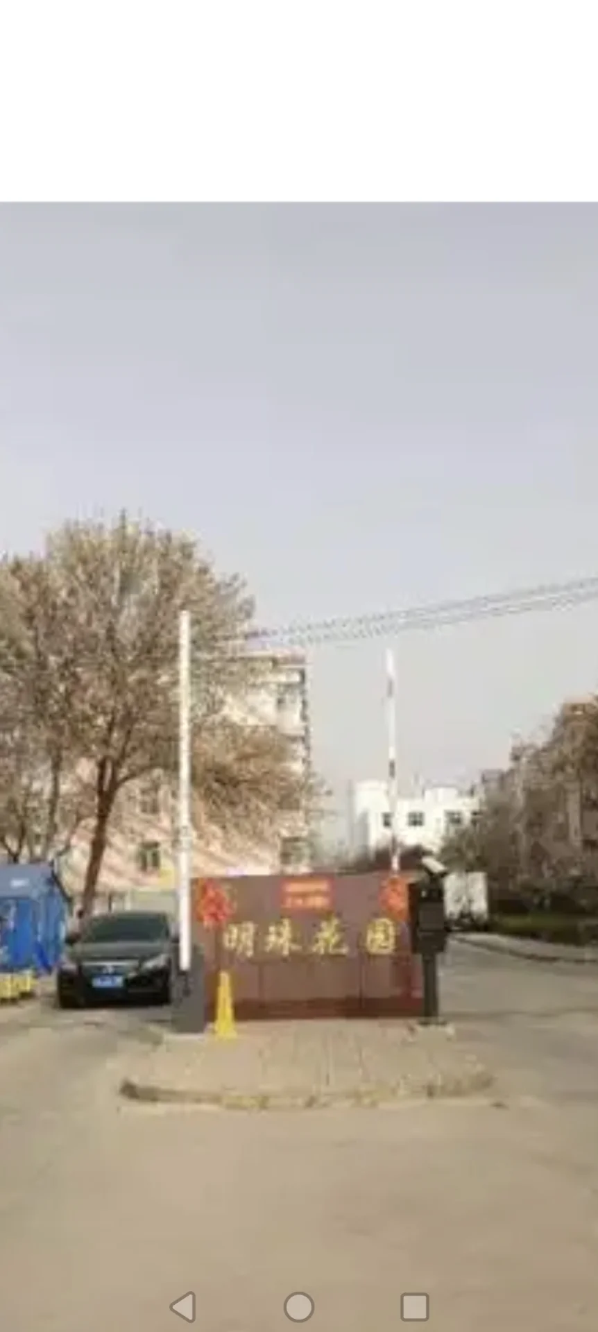 一座带有大型广告牌的建筑立面，建筑风格偏向现代，周围有树木和道路环境。整体氛围显示该区域正在进行商业或开发活动。